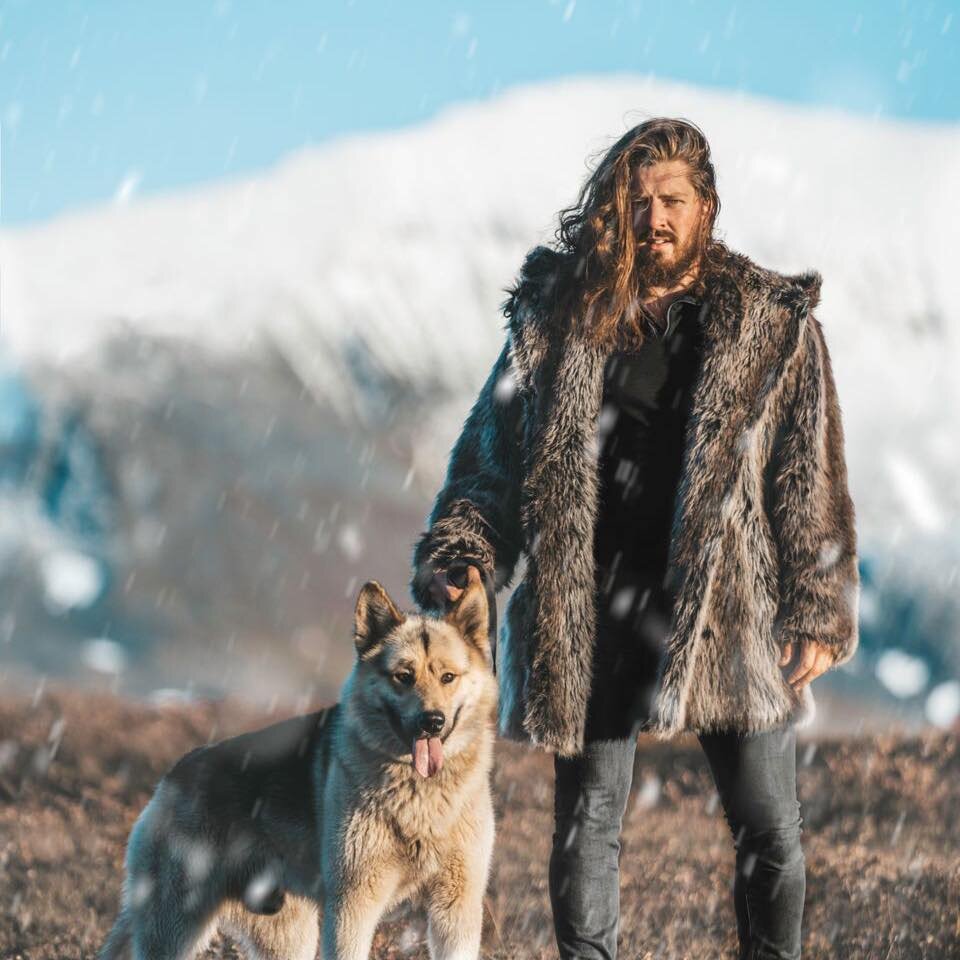 Petter Hetland outside in the snow with his dog, mountains in the background.